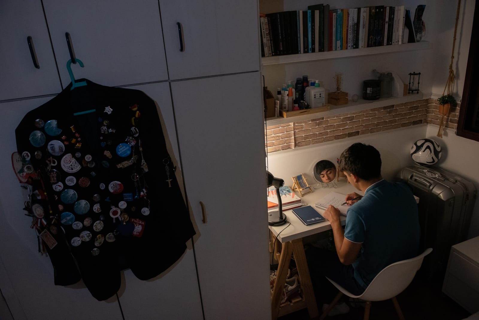 En utbytesstudent gör läxor hemma hos sin värdfamilj, med sin kavaj full av pins hängandes bredvid